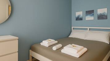 Une chambre à coucher avec un lit, une commode et trois tableaux encadrés accrochés au mur.