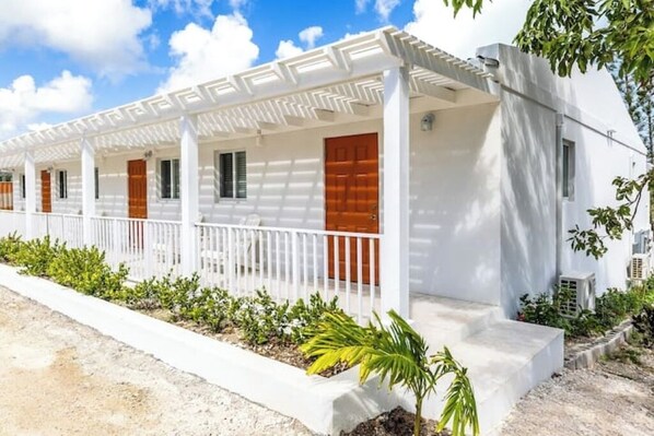 A white building with a covered porch and a wooden door.