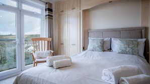 Une chambre avec un grand lit, une chaise et une vue par la fenêtre.