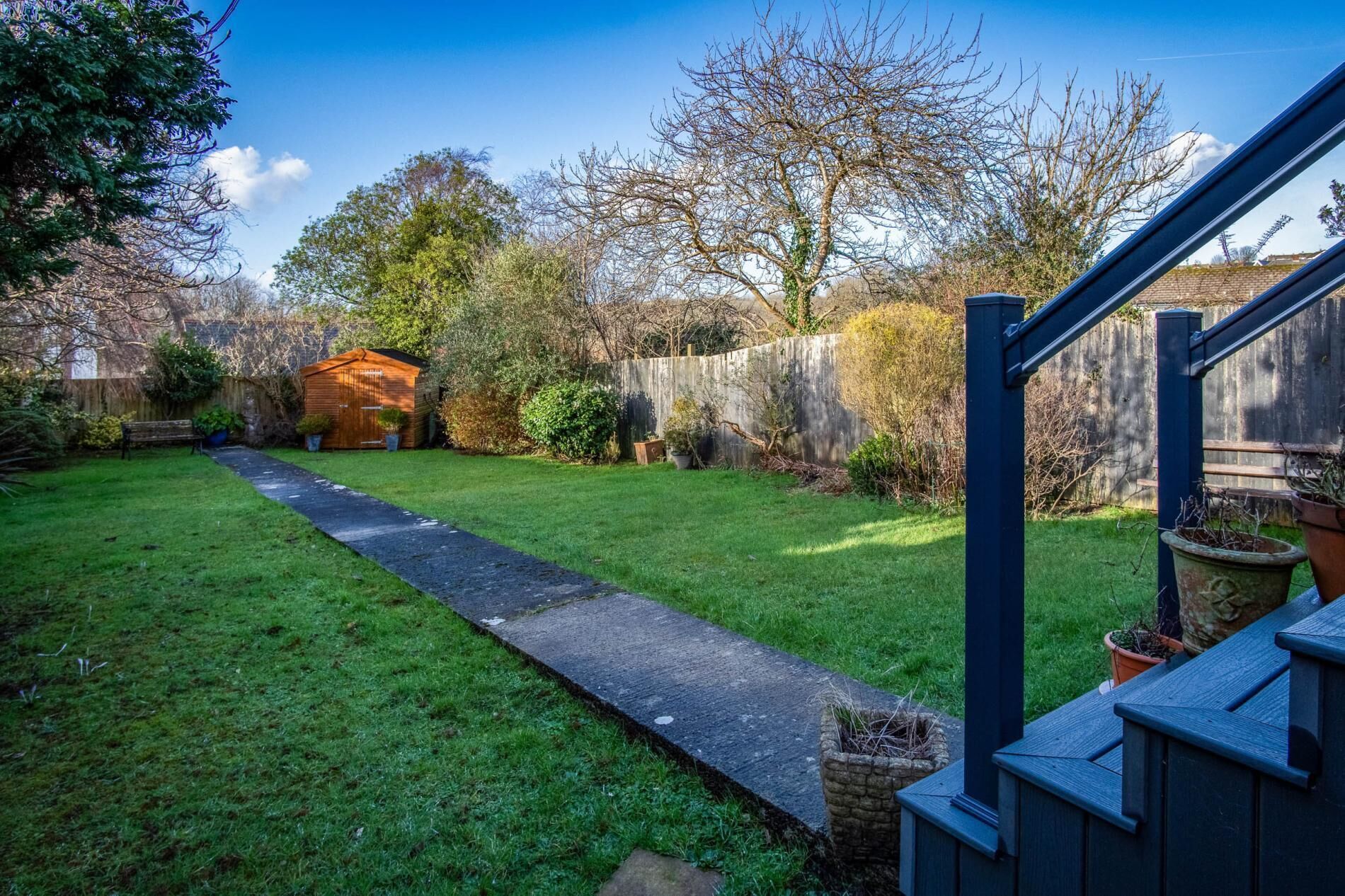 A backyard with a wooden deck, a stone pathway, and a small shed.