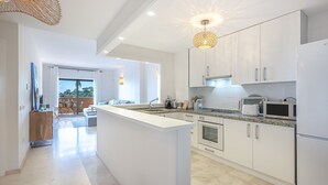 A modern kitchen with white cabinets, a central island, and a view to the outside. - ROCK BAY II 2283 STUNNING VIEWS (Manilva)