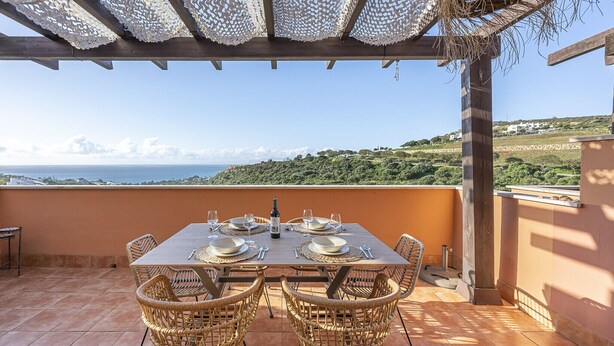A terrace with a table set for dining, wicker chairs, and a view of the sea. - ROCK BAY II 2283 STUNNING VIEWS (Manilva)