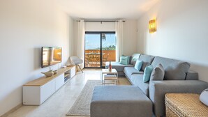 A modern living room with a grey sofa, a flat-screen TV, and a dining area with a table and chairs. - ROCK BAY II 2283 STUNNING VIEWS (Manilva)