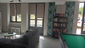 A living room with a sofa, a pool table, a television, a bookshelf, and a window with curtains. - Country cottage, Verette cottage (Écueillé)