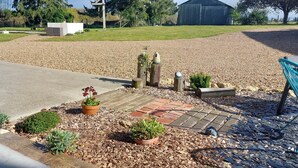 A gravel area with a paved walkway, potted plants, and a metal bench. - Country cottage, Verette cottage (Écueillé)