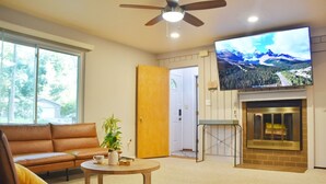 Ein Wohnzimmer mit einer Ledersofa, einem Couchtisch, einem Kamin und einem an der Wand befestigten Fernseher.