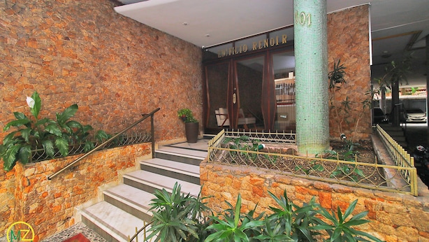 Una escalera conduce a la entrada de un edificio, con un muro de piedra y una barandilla de metal.