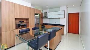Una cocina moderna con armarios de madera, una mesa de comedor de vidrio y sillas negras.