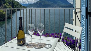 A balcony with a table, two wine glasses, and a bottle of wine. - Villa Rêverie - Boutique Hotel (Bellano)
