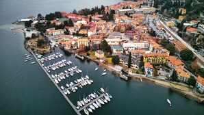 An aerial view of a coastal town with a marina filled with boats, surrounded by buildings with red roofs. - Villa Rêverie - Boutique Hotel (Bellano)