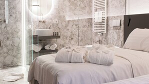 A modern bathroom with a glass shower enclosure, a marble wall, a sink, and a bed with towels. - Villa Rêverie - Boutique Hotel (Bellano)