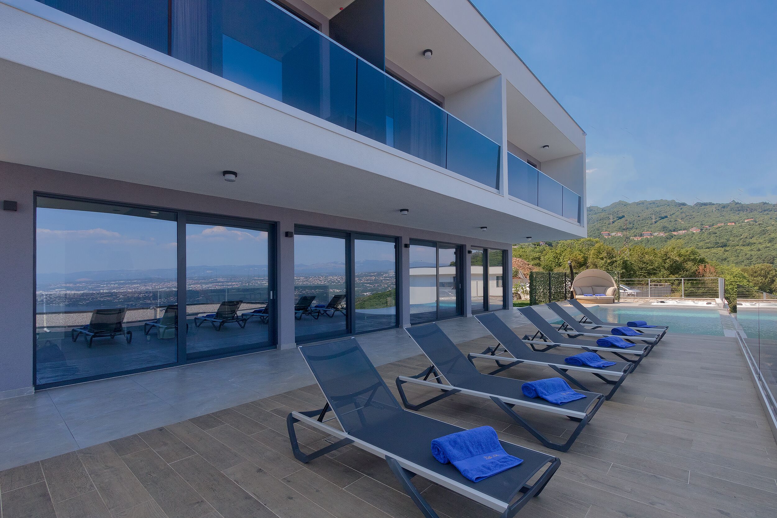 Eine moderne Lounge-Bereich im Freien mit Liegestühlen und Pool, mit Blick auf eine malerische Landschaft.