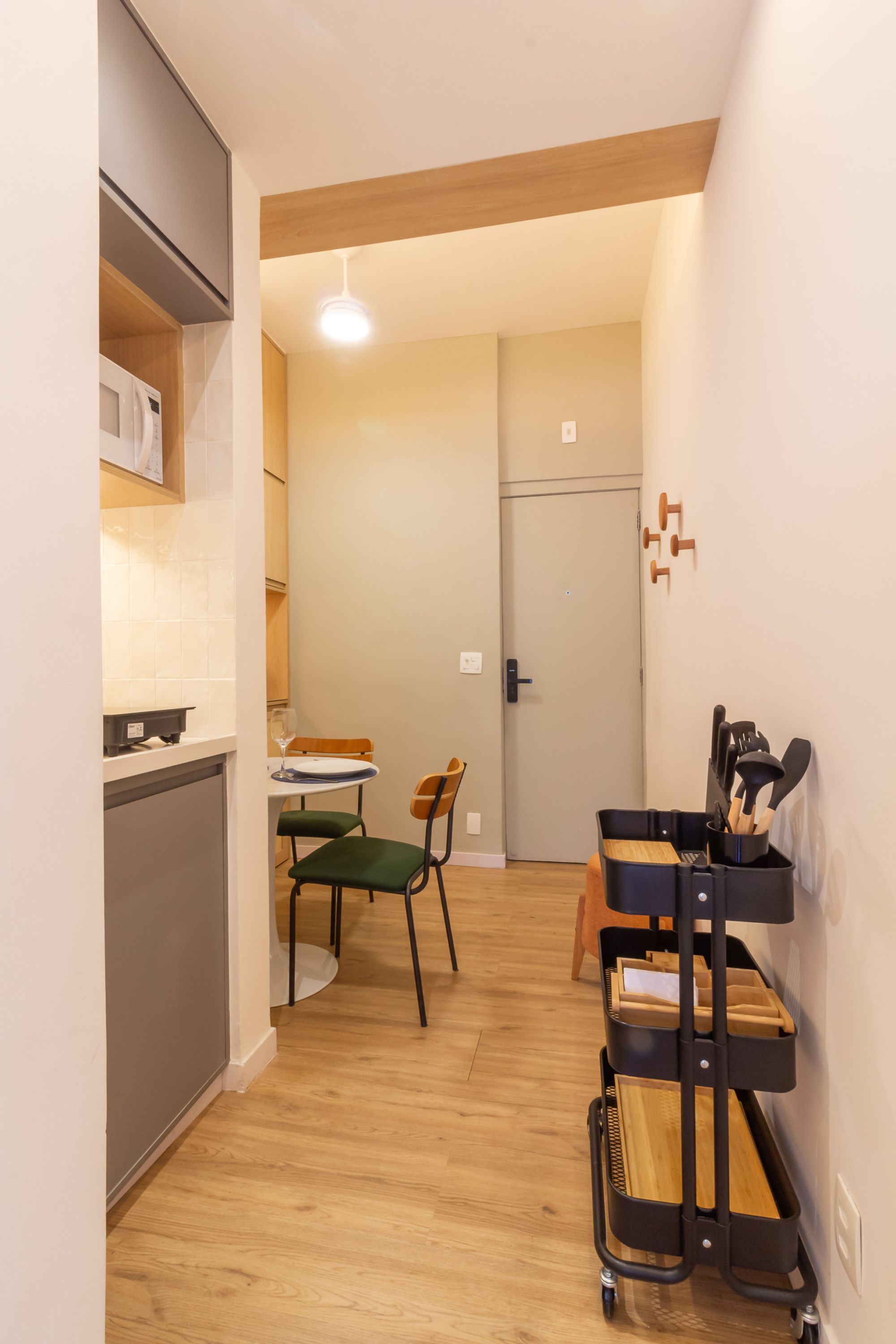 A compact kitchen with a dining area, a wooden ceiling, and a wall-mounted utensil holder.