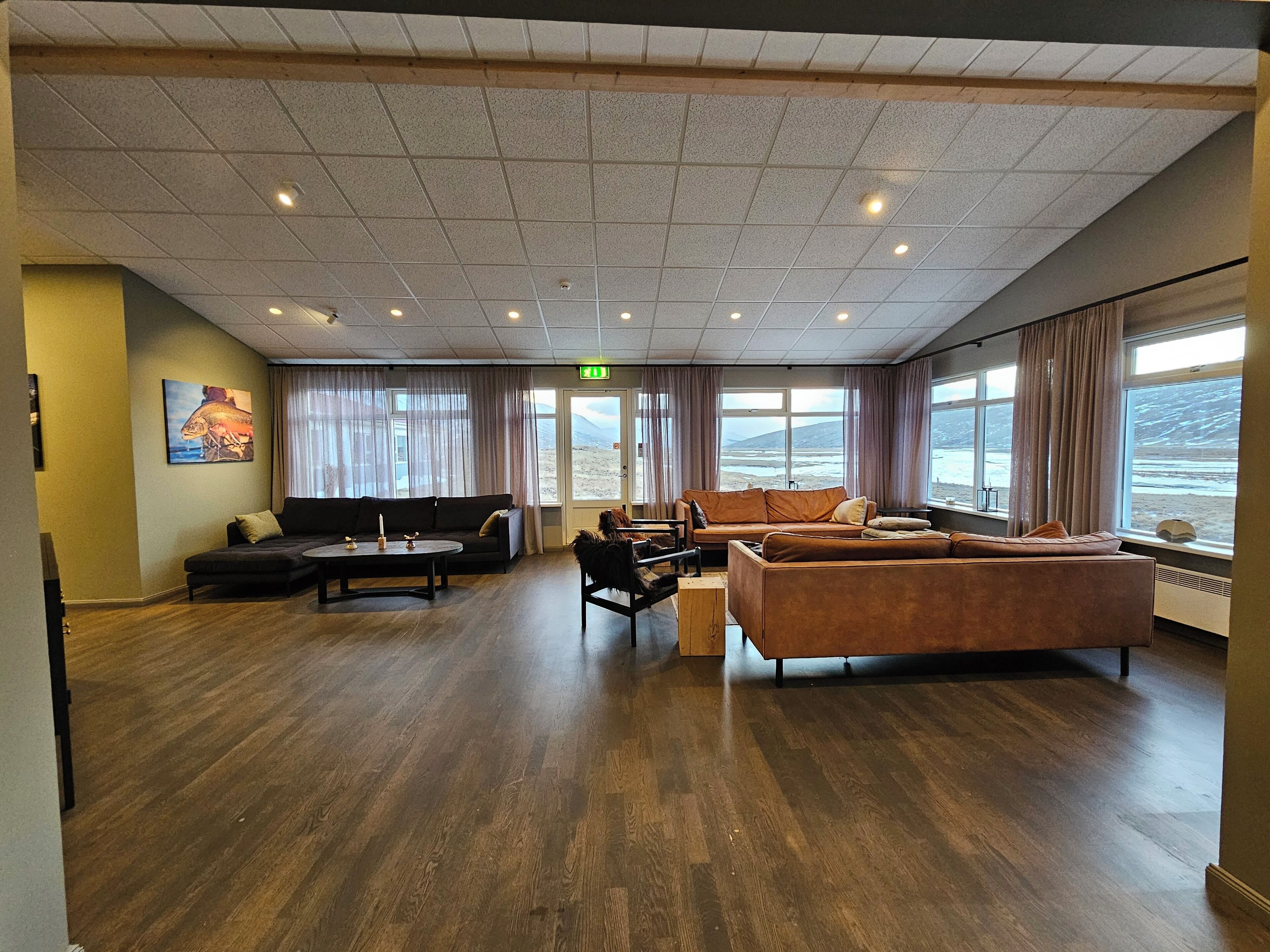 A spacious lobby with a wooden floor, two sofas, a coffee table, and large windows offering a view of the beach.