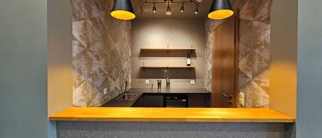 A modern kitchen with a built-in oven, a sink, and two pendant lights.