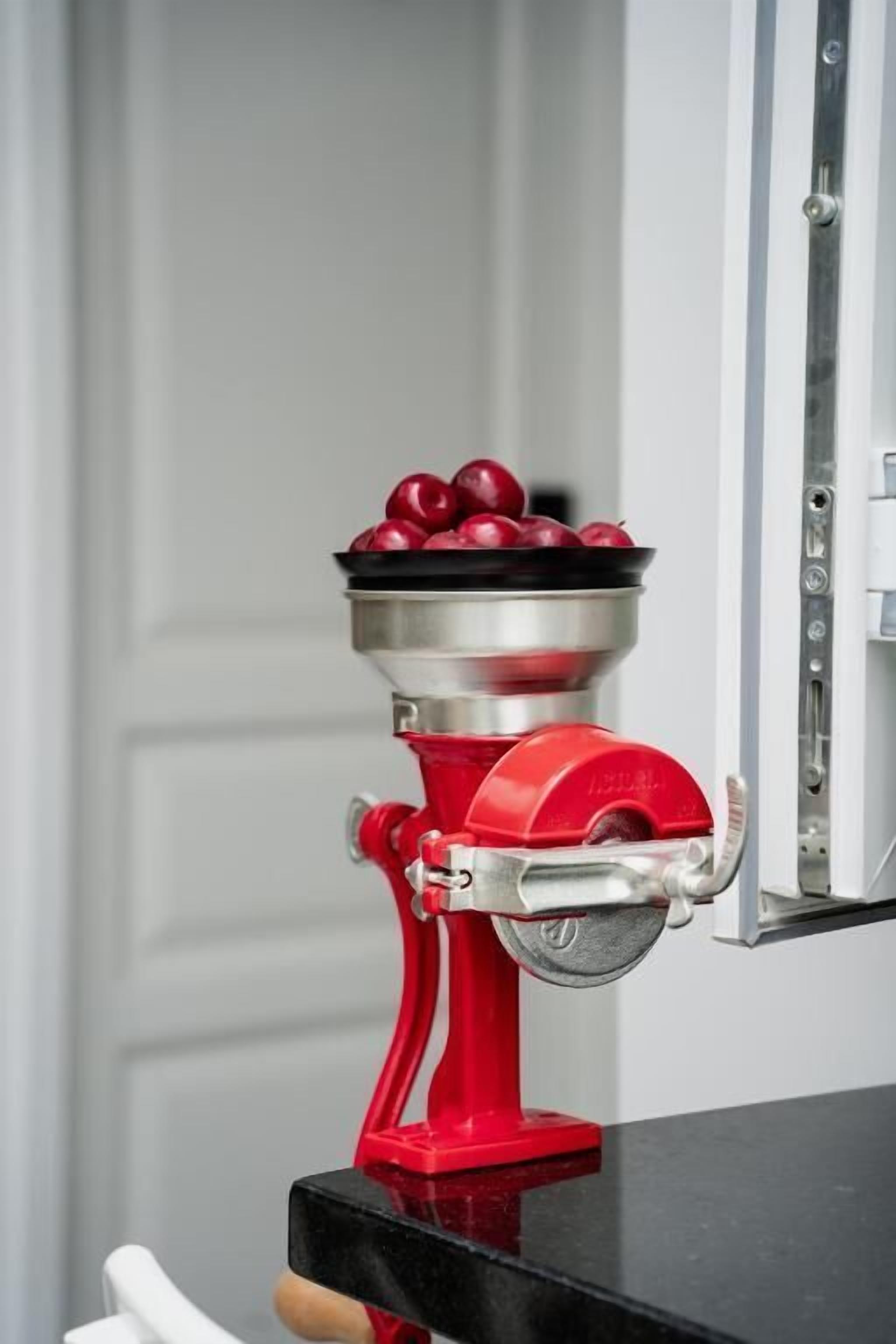 Un electrodoméstico rojo con un bol de manzanas rojas encima.