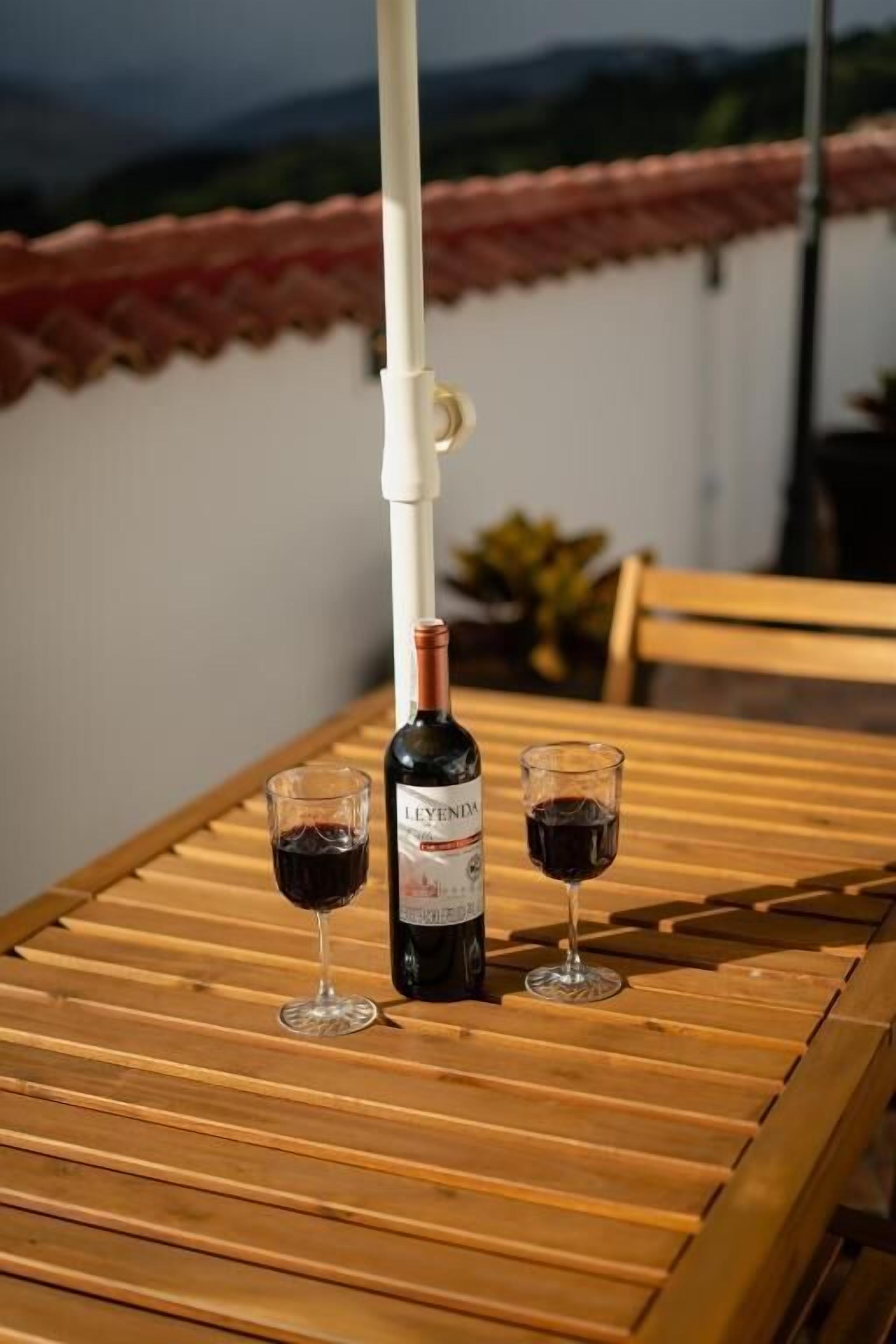 A bottle of Leyenda wine on a wooden table with two glasses of wine.