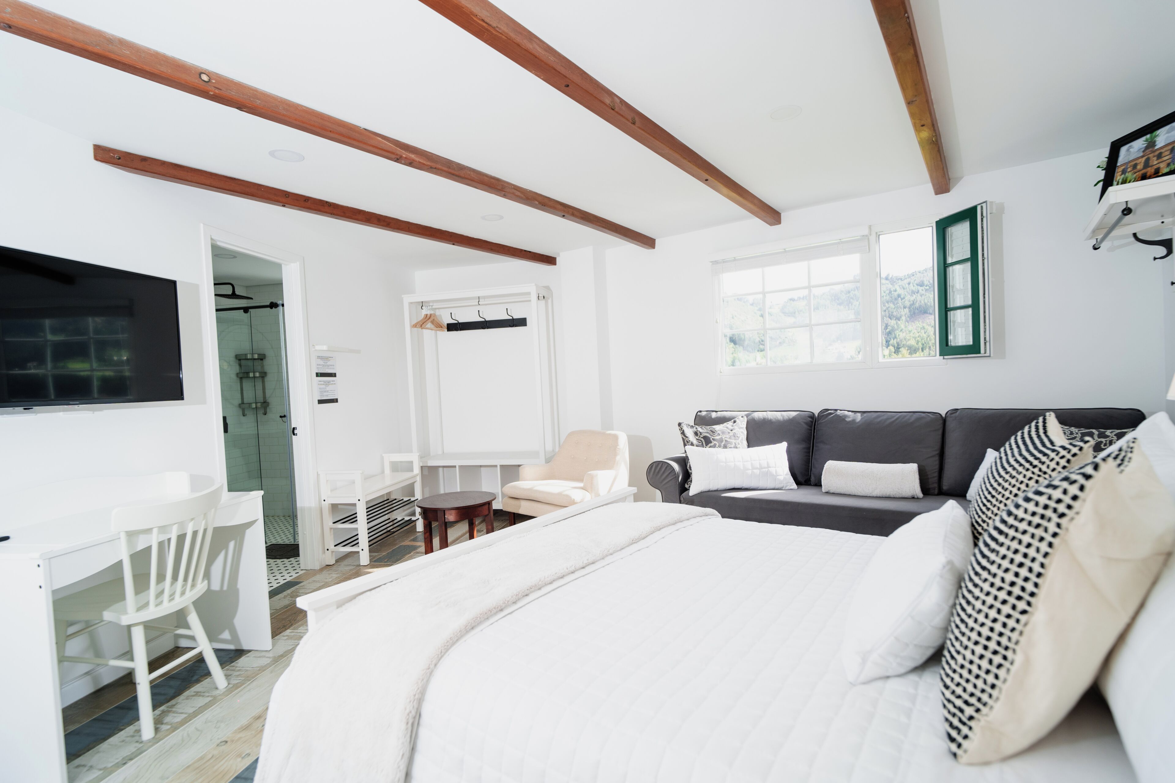 Un dormitorio con cama, escritorio, silla, sofá y ventana.