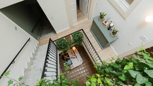 A staircase with a railing, a seating area with a table and chairs, and potted plants. - Studio 1 apartment in Ortigia (Siracusa)