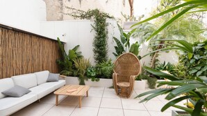 A modern outdoor seating area with a white sofa, a wooden coffee table, and a wicker chair. - Studio 1 apartment in Ortigia (Siracusa)