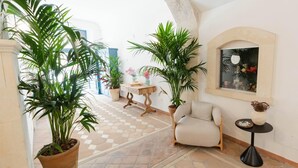 A spacious hallway with a checkered floor, a comfortable armchair, and several potted plants. - Studio 1 apartment in Ortigia (Siracusa)