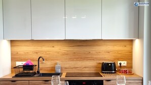 A modern kitchen with wooden cabinetry, a built-in sink, a toaster, and a fruit bowl on the counter. - Apartament Let's Sea 82 - 365PAM (Gaski)