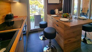 A modern kitchen with a wooden countertop, a built-in stove, and a large window with a view of trees. - Apartament Let's Sea 82 - 365PAM (Gaski)
