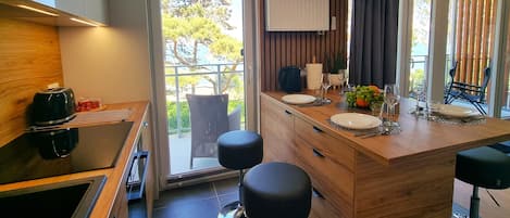 A modern kitchen with a wooden countertop, a built-in stove, and a large window with a view of trees.