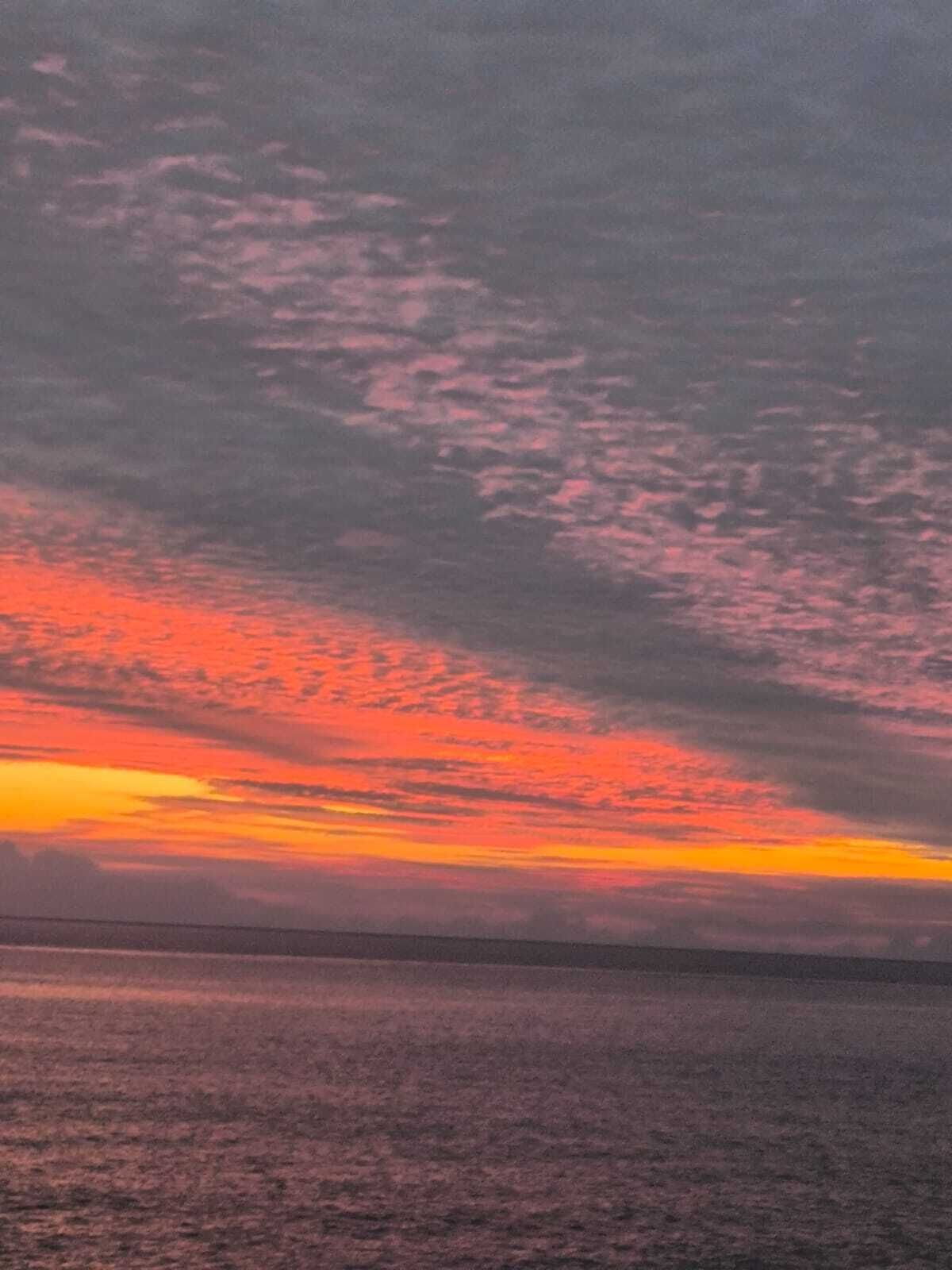Un atardecer sobre una masa de agua con una costa lejana.