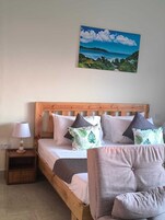 Un dormitorio con una cama de madera, una mesita de noche, una lámpara, una silla y un cuadro de un paisaje.