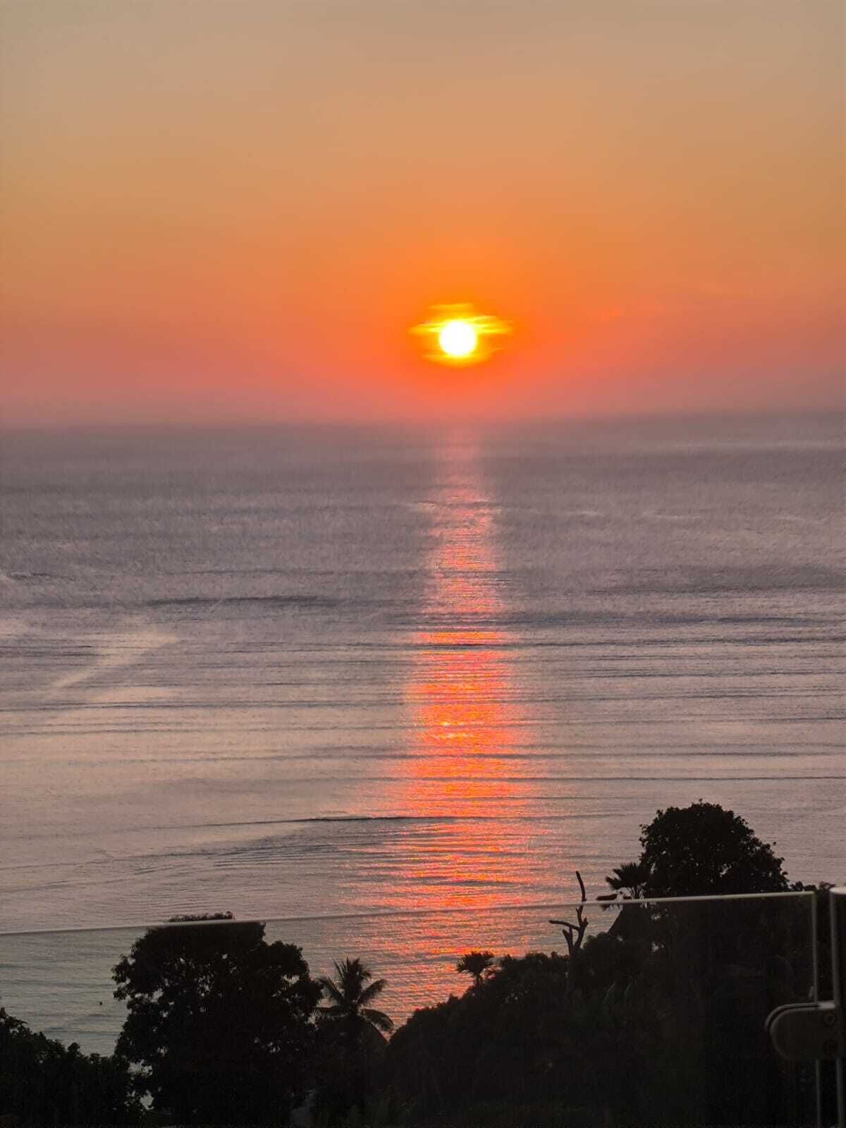 Un coucher de soleil sur une mer calme, avec un horizon dégagé.