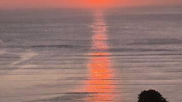 Un coucher de soleil sur une mer calme, avec un horizon dégagé.
