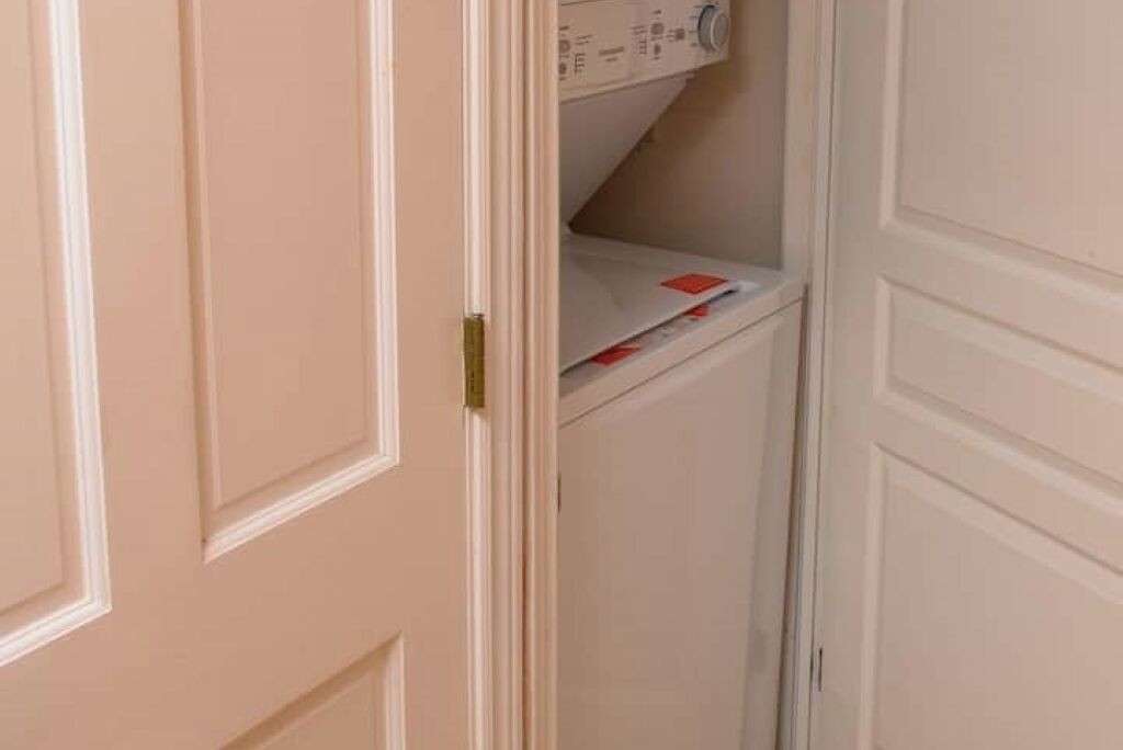 A closed door with a white handle and a small shelf with a white box and some papers.