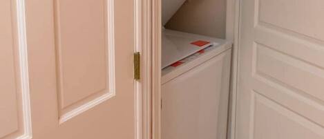 A closed door with a white handle and a small shelf with a white box and some papers.