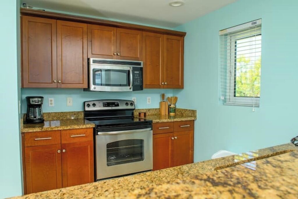 A kitchen with wooden cabinets, a microwave, an oven, and granite countertops.