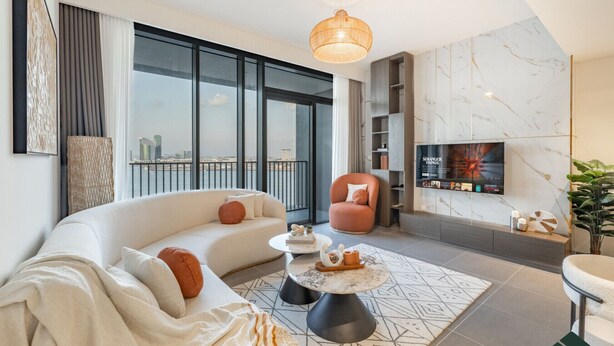 A modern living room with a sofa, armchair, coffee table, and a TV mounted on the wall. - Serene 2BR | Panoramic Sea View | Creek Edge | BMS (Dubai)