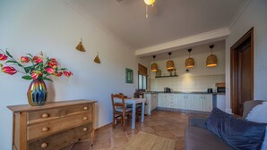 A kitchen with white cabinets, a dining table with chairs, and a vase with flowers on a wooden dresser. - Boutique B&B Casa La Calera 15+/ Caminito del Rey-15 min/Ronda-25 min/Town-5 min (Teba)
