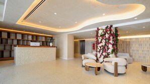 A modern lobby with a reception desk, seating area, and a decorative floral arrangement. - Hotel Vibra Yamm Sunset - Adults Only (Sant Antoni de Portmany)