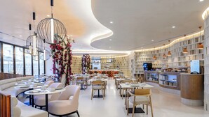 A modern restaurant with a curved ceiling, seating arrangements, and a bar area. - Hotel Vibra Yamm Sunset - Adults Only (Sant Antoni de Portmany)