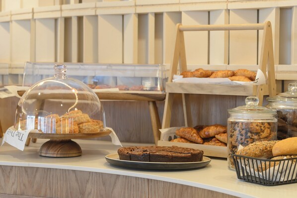 Mostrador de panadería con diversas opciones de repostería, incluyendo un pastel cubierto y frascos de galletas.