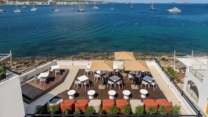 A rooftop terrace with outdoor seating, a view of the sea, and sailboats. - Hotel Vibra Yamm Sunset - Adults Only (Sant Antoni de Portmany)