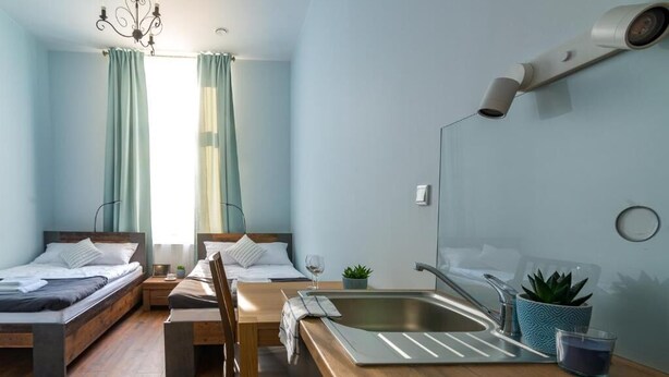 Una habitación de hotel moderna con dos camas, un escritorio de madera, un lavamanos y un espejo.