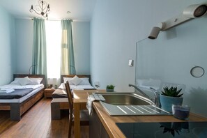 Ett modernt hotellrum med två sängar, ett skrivbord i trä, ett handfat och en spegel.