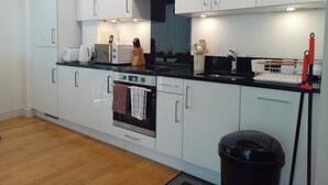 A modern kitchen with white cabinets, a black countertop, a built-in oven, and a coffee maker. - 4 Guests - Marina Point East Escape in Kent (Chatham)