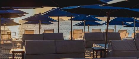 A beachside lounge with rows of sun loungers and umbrellas, overlooking the sea.