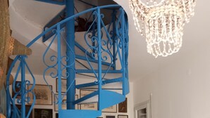 Una escalera en espiral azul en una habitación con pared blanca y una araña.