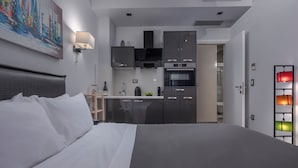 Une chambre d’hôtel moderne dotée d’un grand lit, d’une kitchenette équipée d’un four à micro-ondes, d’un four et de placards, ainsi que d’un tableau accroché au mur.