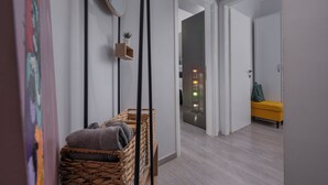 Un couloir avec un banc en osier, une petite plante en pot et un miroir accroché au mur.