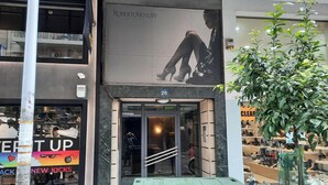 Une vitrine ornée d’une grande publicité pour Roberto Venuti Milano, une boutique de chaussures.