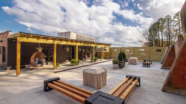 An outdoor patio area with a covered seating area, wooden benches, and potted plants.